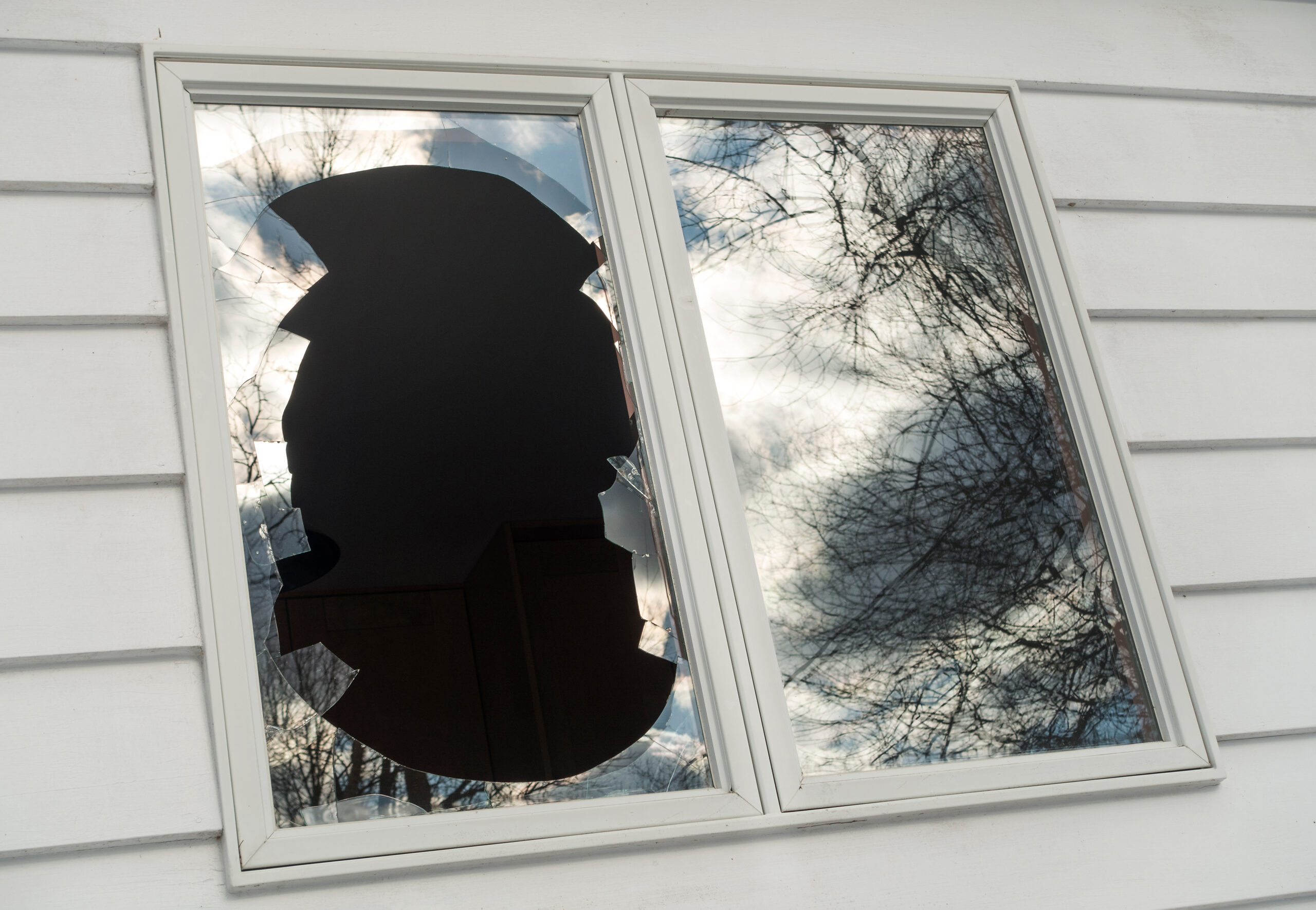 vandalized broken window on house with cracked glass